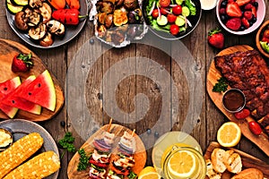 Summer BBQ or picnic food frame over a rustic wood background, top down view with copy space