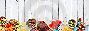 Summer BBQ or picnic food long border, top view over a white wood banner background