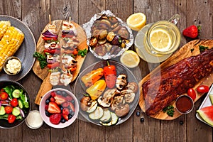 Summer BBQ or picnic food table scene, top down view over a dark wood background