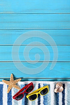 Summer beach background border, sunglasses, towel, starfish, blue copy space, vertical