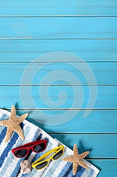 Summer beach background border, sunglasses, towel, starfish, blue wood copy space, vertical photo