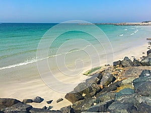 Summer beach background. Rocky beach with black stones. White b