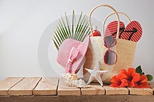 Summer beach bag and hibiscus flowers on wooden table. Summer holiday vacation concept. View from above