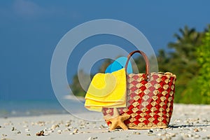 Summer beach bag with shell, towel on sandy beach