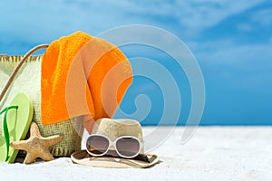 Summer beach bag with starfish,towel,sunglasses and flip flops on sandy beach