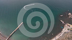 Summer beach on blue sea with umbrellas and deck chairs in resort city drone view. Aerial top shooting bright blue sea