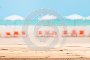 Summer beach chair umbrella blur with wooden table top for montage products background advertising space