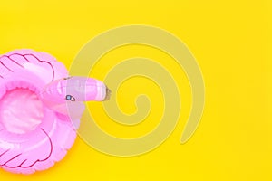 Summer beach composition. Simply minimal design with pink Inflatable flamingo isolated on yellow background. Pool float party,