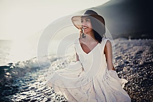 Summer beach fashion woman in white dress enjoying summer and sun,walking the beach near blue sea.Relaxed emotional sensual