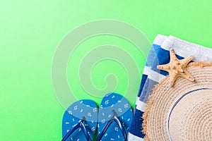 Summer beach flat lay accessories. Sunscreen straw hat, flip flops, towel and seashells on colored Background. Travel holiday