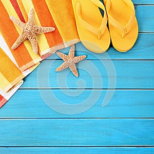 Summer beach objects border, flip flops, starfish blue wood background
