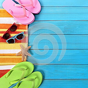 Summer beach objects border, sunglasses, flip flops, blue wood background copy space