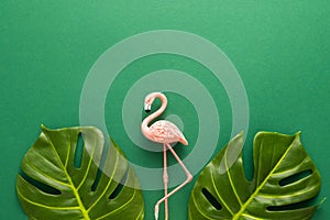 Summer beach party concept. Pink flamingo and tropical leaf monstera on green background. Flat lay, copy space