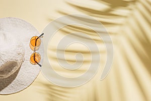 Summer beach rest concept background with sunhat, colored sunglasses on sandy color paper. Flat lay with woman accessory
