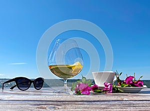 Summer beach restaurant glass of juice sunglasses and cup of coffee with roses flowers on table top ,horizon sea and blue sky at b