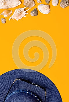 Summer beach sea accessories. Blue female straw hat, sunglasses, shells, starfish on yellow background top view flat lay