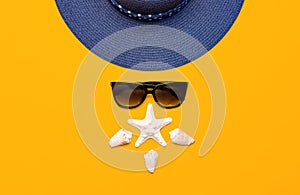 Summer beach sea accessories. Blue female straw hat, sunglasses, shells, starfish on yellow background top view flat lay copy