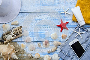 Summer beach sea concept. Blue Wooden background with different accessories, shells, starfish, towel, sunscreen, sand