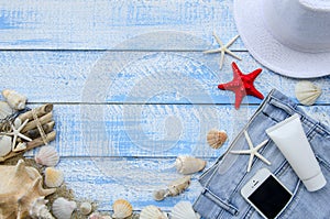 Summer beach sea concept. Blue Wooden background with different accessories, shells, starfish, towel, sunscreen, sand