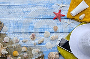 Summer beach sea concept. Blue Wooden background with different accessories, shells, starfish, towel, sunscreen, sand