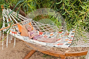 Summer beach tropical vacation with kids. Cute happy little caucausian girl laying in a hammock