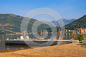 Summer beach vacation. Beautiful Mediterranean landscape with beach umbrellas on sunny summer day. Montenegro, Kotor Bay