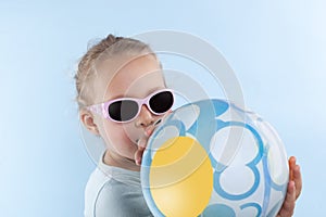 Summer. Beautiful small girl with ball and sunglasses.