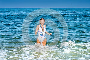 Summer. Beautiful tanned woman in swimsuit is coming out of the ocean