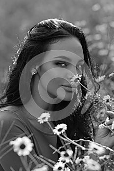 Summer beauty. Beautiful woman in a field of daisies. Sensual Woman in a field of summer flowers. Outdoor portrait of