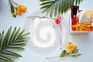 Summer beauty concept background with stationery card, pen, tropical leaves, cosmetic products and alstroemeria flowers