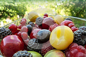 Summer berries raspberry red currant strawberry gooseberry and sweet cherry in a glass bowl