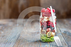 Summer berries smoothie in mason jar on rustic wooden table