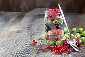 Summer berries smoothie in mason jar on rustic wooden table