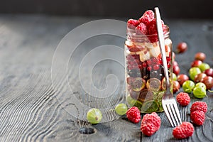 Summer berries smoothie in mason jar on rustic wooden table