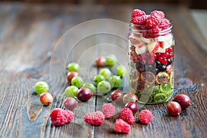 Summer berries smoothie in mason jar on rustic wooden table