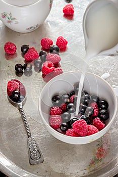 Summer berries in white cup on old metal tray.