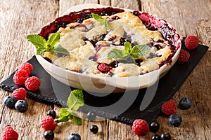 Summer berry cake with raspberry berries, currants and blueberries close-up in a baking dish. horizontal