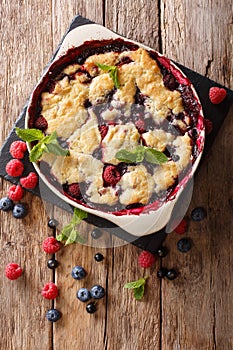 Summer berry cake with raspberry berries, currants and blueberries close-up in a baking dish. vertical top view