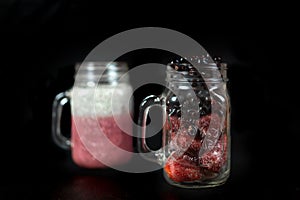 Summer berry cocktail with chia seeds in vegetable milk in glass glasses on a dark background.