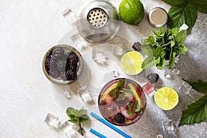 Summer blackberry mojito or blackberry soda. Refreshing summer drink with blackberry, mint, lime and ice on a stone table.