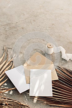 Summer boho wedding stationery still life. Blank greeting cards, envelope mock-ups and silk ribbon. Dry palm leaves on