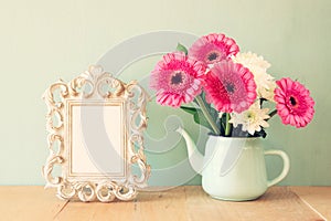 Summer bouquet of flowers and victorian frame on the wooden table with mint background. vintage filtered image