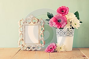 Summer bouquet of flowers and victorian frame on the wooden table with mint background. vintage filtered image