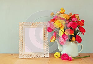 Summer bouquet of flowers and victorian frame on the wooden table with mint background. vintage filtered image