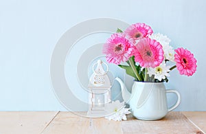 Summer bouquet of flowers and vintage lantern on the wooden table with mint background. vintage filtered image