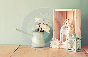 Summer bouquet of flowers and vintage lantern on wooden table with mint background. vintage filtered image
