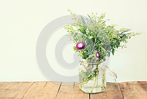 Summer bouquet of flowers on the wooden table with mint background. vintage filtered image