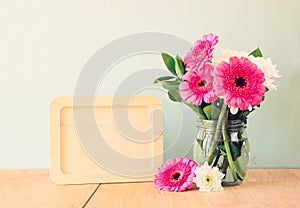 Summer bouquet of flowers on the wooden table and wooden board with room for text with mint background. vintage filtered image