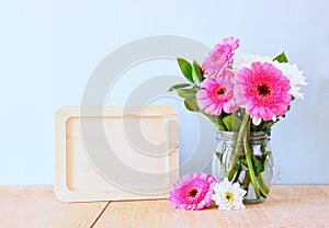 Summer bouquet of flowers on the wooden table and wooden board with room for text with mint background. vintage filtered image