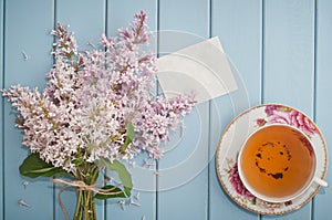 Summer bouquet of gentle blooming lilac with card and tea